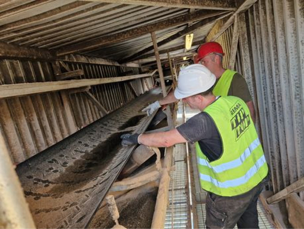 Zwei Servicetechniker prüfen ein Förderband in einer Förderanlage.