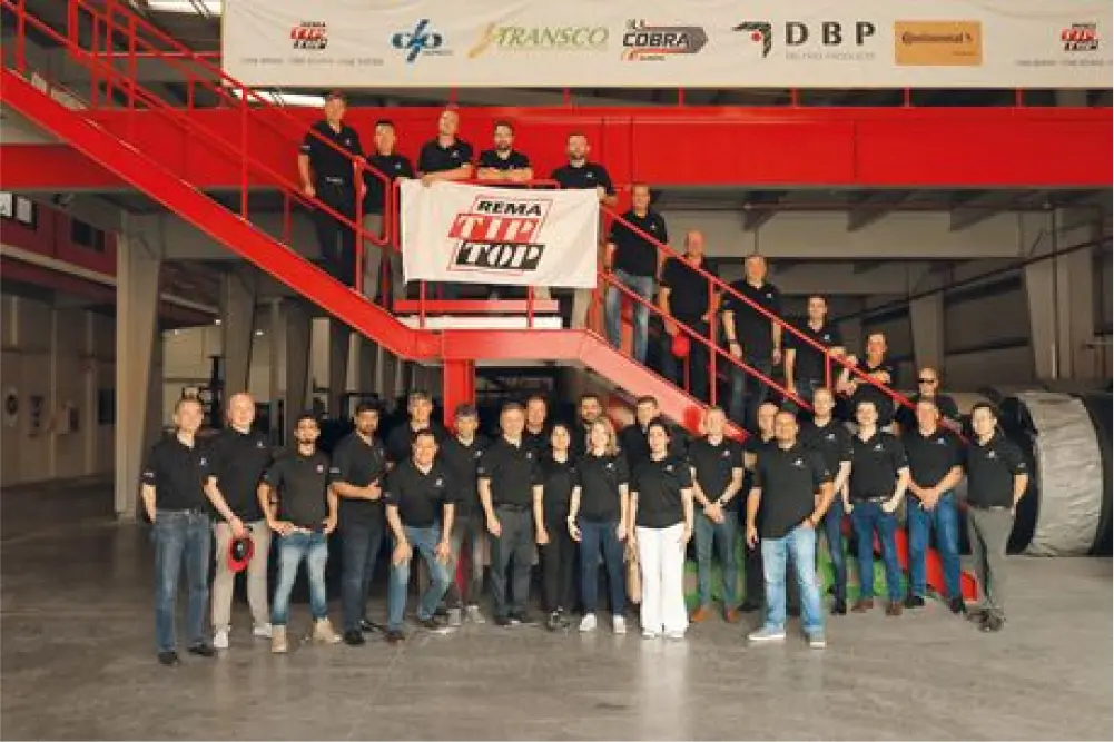 Gruppenfoto von Mitarbeitenden in einer Werkhalle (REMA TIP TOP).