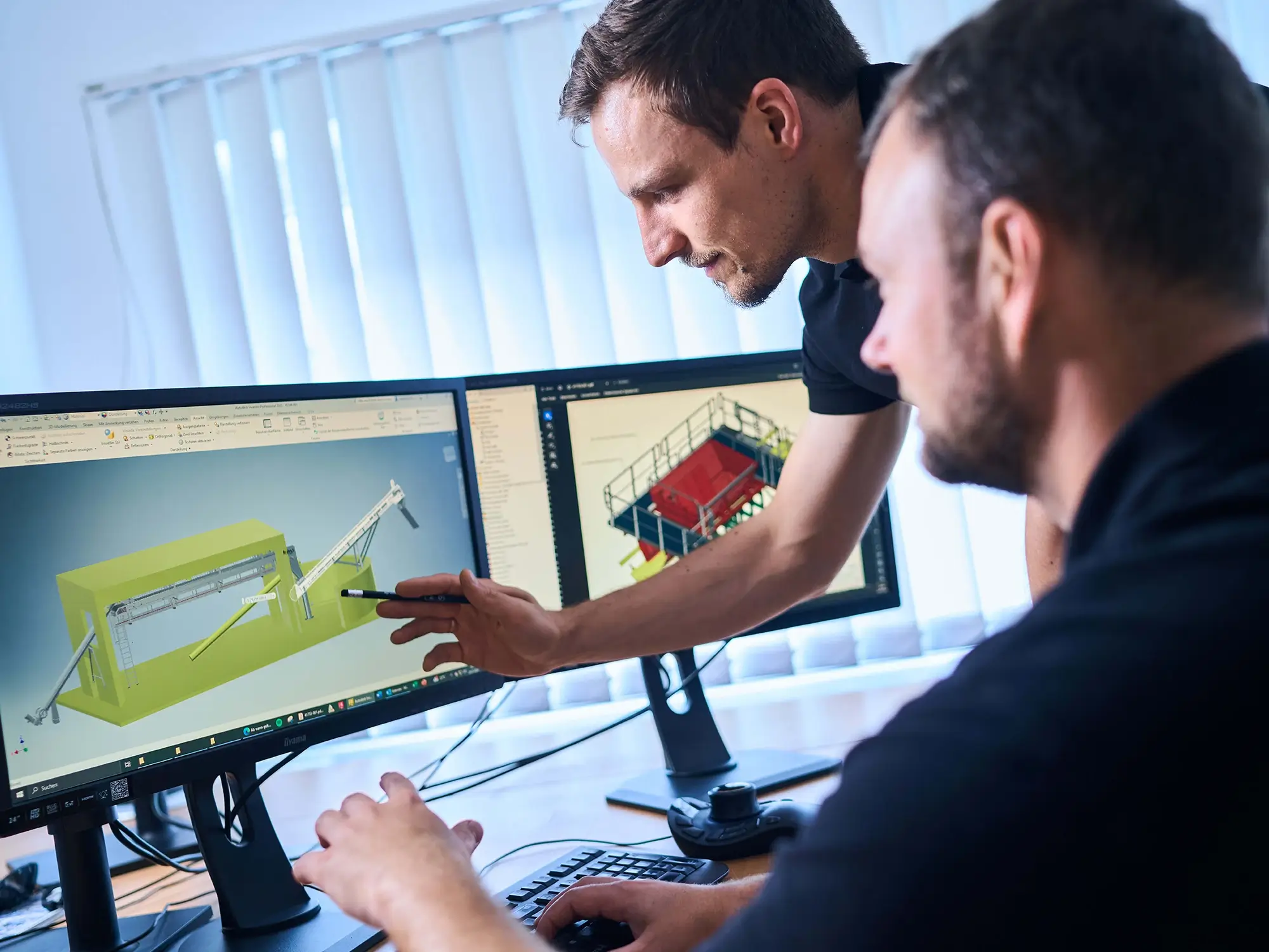Zwei Mitarbeiter planen eine Anlage anhand einer CAD Zeichnung