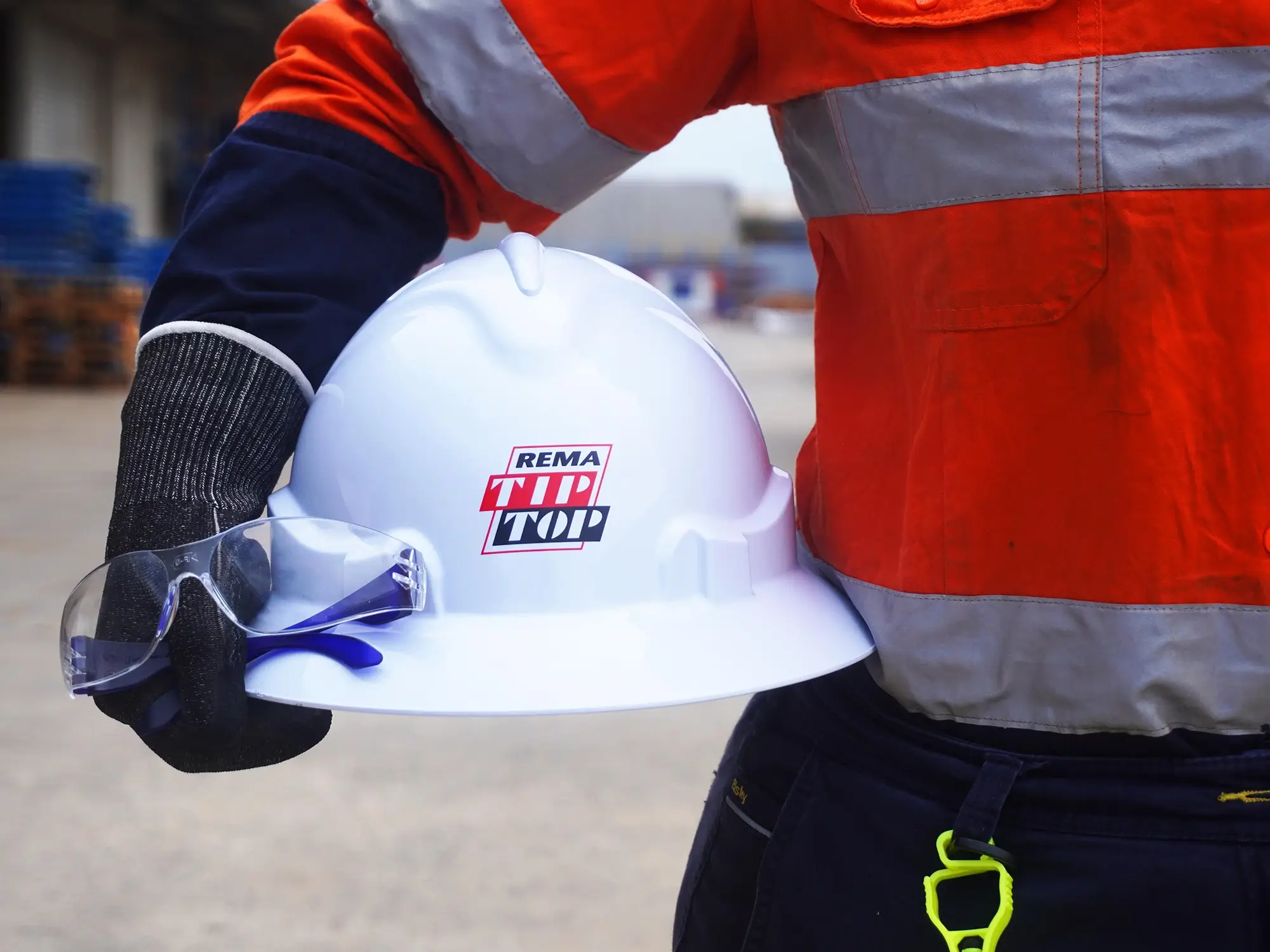 Ein Helm und eine Schutzbrille in der Hand eines Mitarbeiter zeigt die Arbeitssicherheit