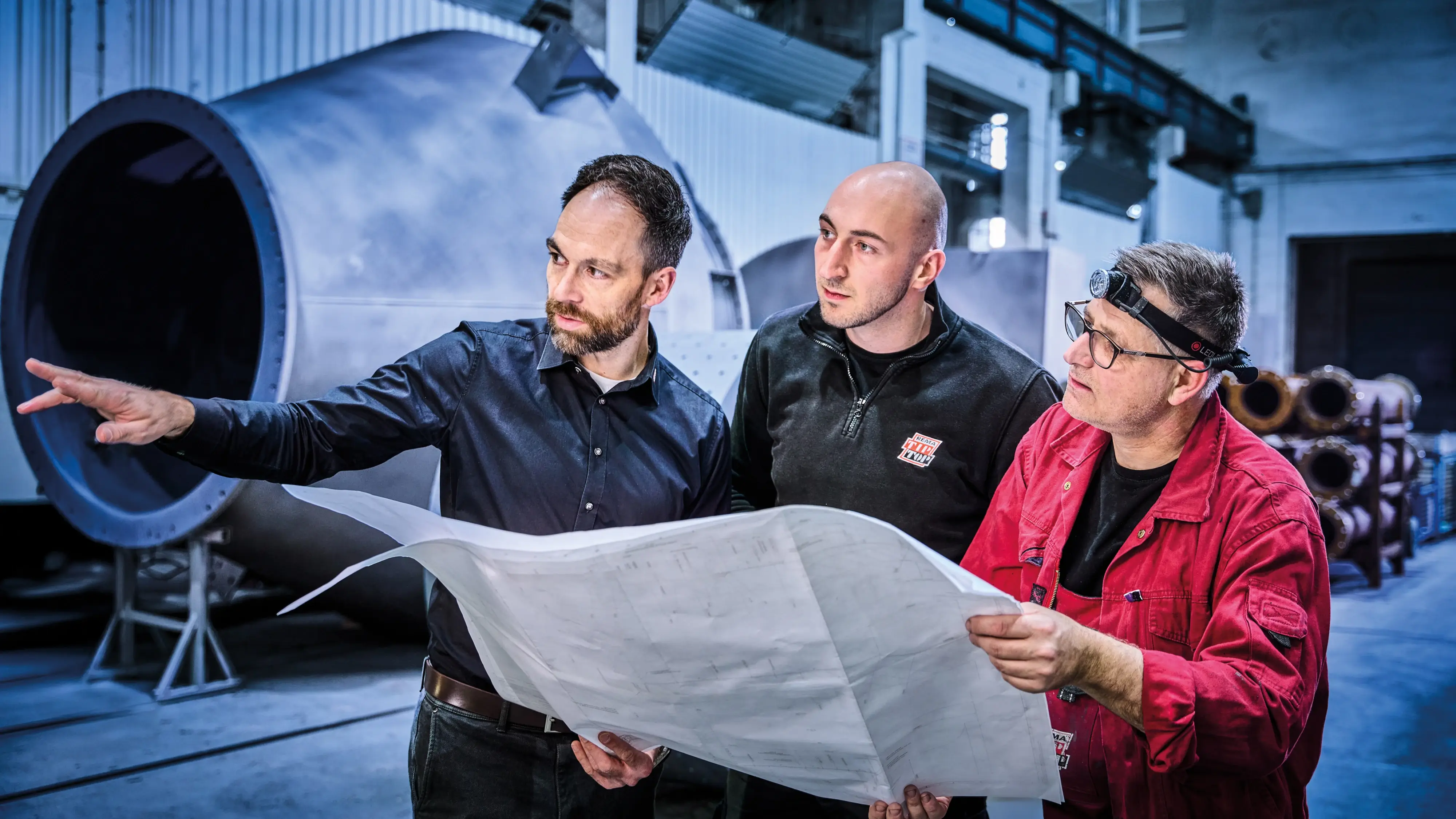 Drei Mitarbeiter planen anhand einer technischen Zeichnung